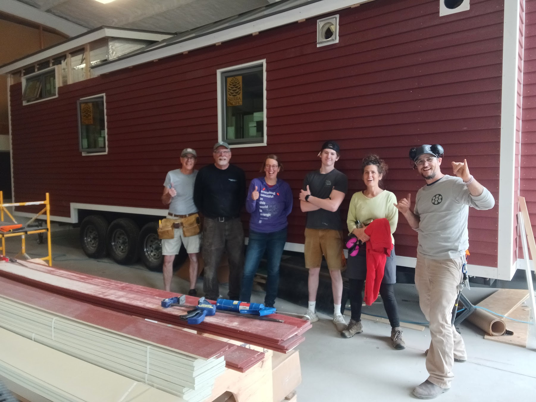 Six smiling people standing in front of the tiny house